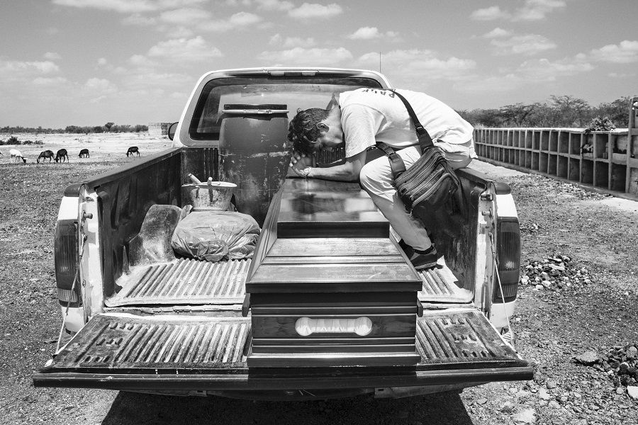 Luis Arevalo, a migrant from Venezuela, sits in the back of a pickup truck mourning his sister Luisana, in Riohacha, Co- lombia.